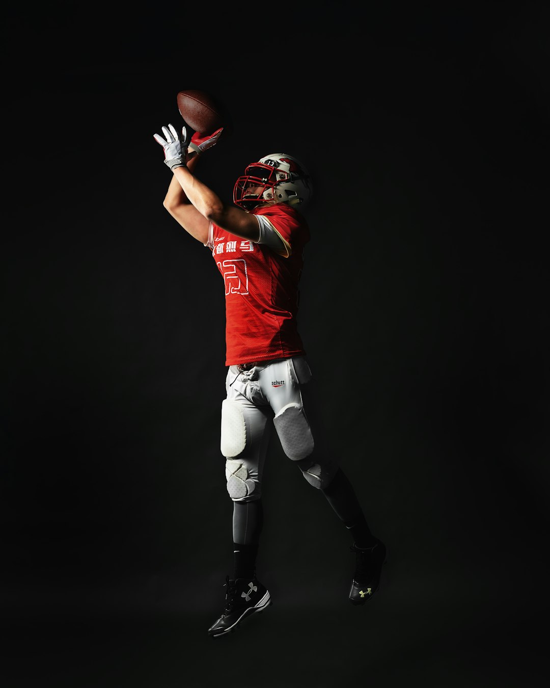 a football player is jumping in the air to catch a ball quarterback throwing football, nfl stadium lights, football action shot