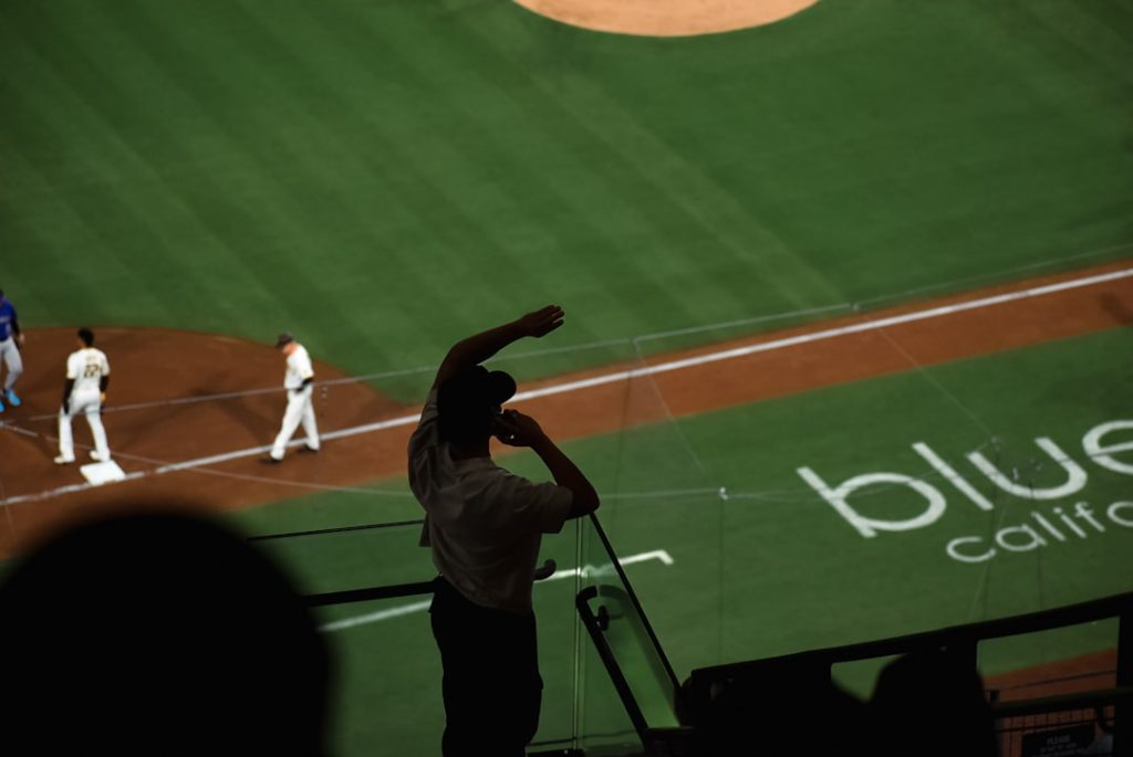 A group of men standing on top of a baseball field baseball pitcher throwing fastball, close up mound action, stadium lights night game