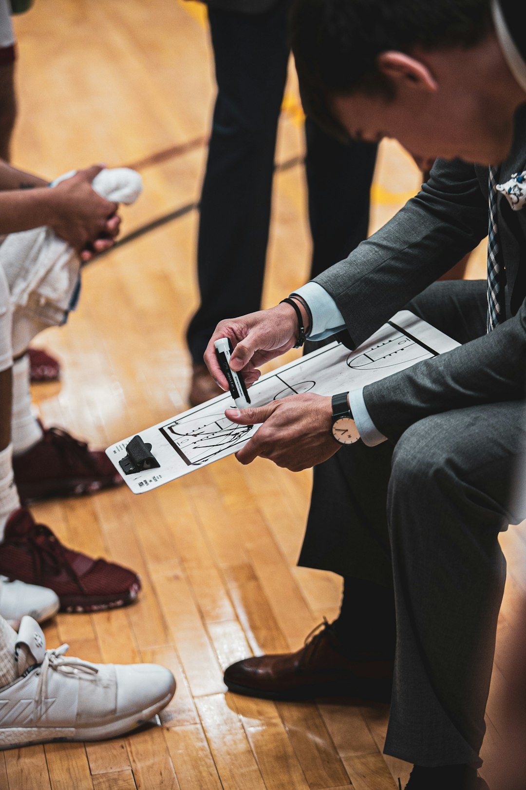 a group of people sitting on top of a wooden floor basketball shoe contract signing, sports sponsorship deal, athlete commercial shoot