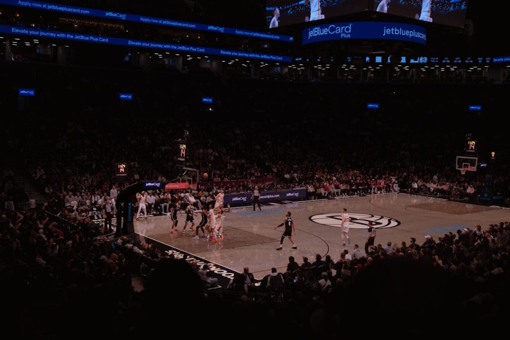 Basketball game in a crowded arena at night stadium. nba point guard driving, arena lights, intense basketball moment