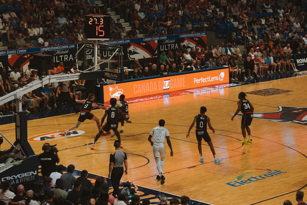 Basketball players compete on the court during a game. NBA court wide shot, tall players under basket, height comparison