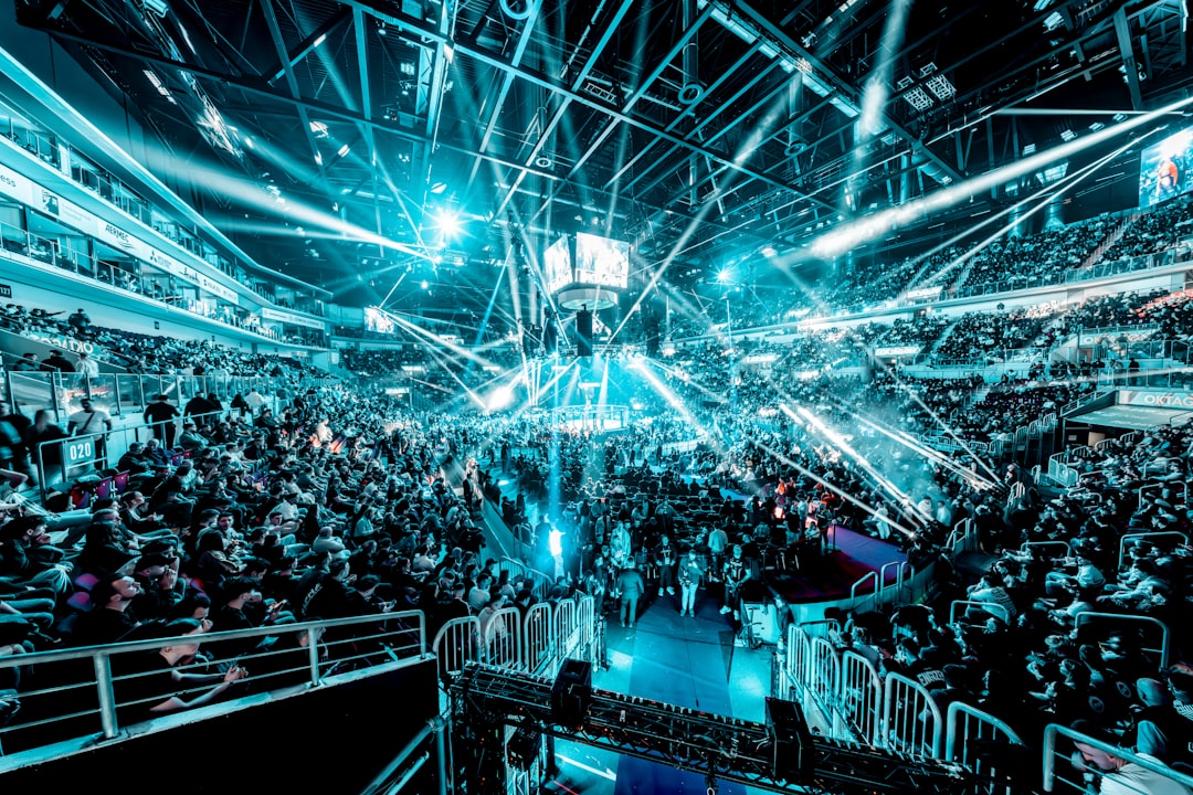 Crowd at a concert with bright blue stage lights esports arena, gaming tournament stage, large crowd, multiplayer battle game screen