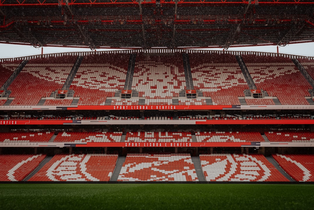 Empty stadium seats with a green field below Manchester United lineup formation, football pitch graphic, red team formation