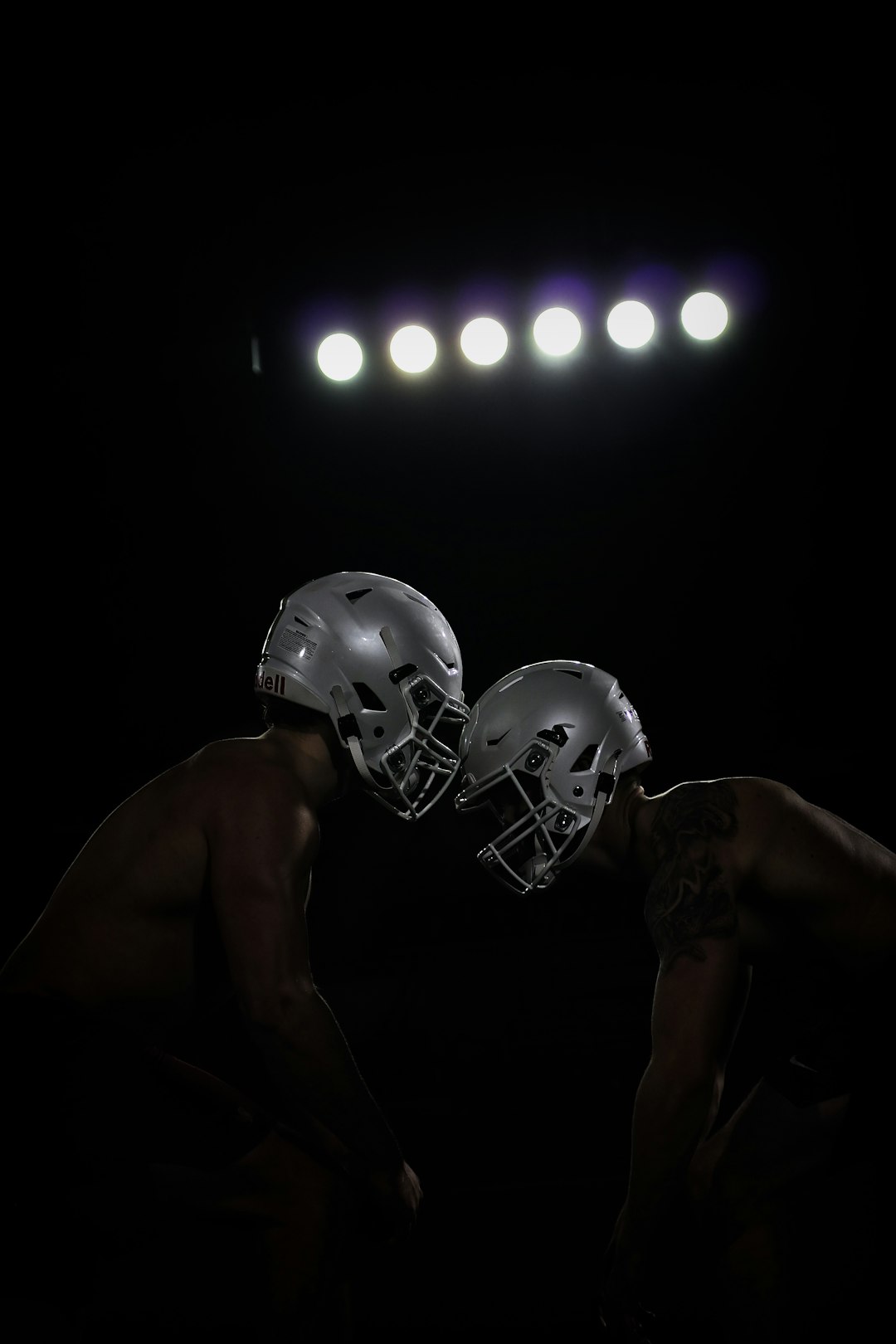 two football players are facing each other in the dark NFL defensive lineman sack quarterback, intense football tackle, stadium lights night game