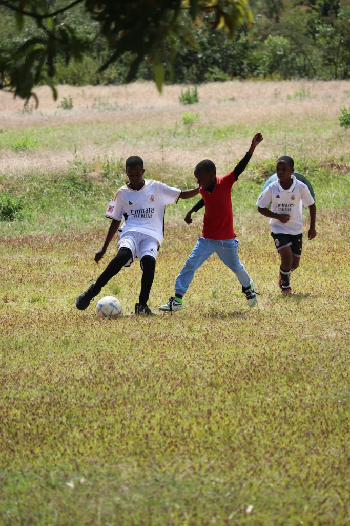 Young boys are playing soccer on a grassy field. midfield battle football match, player marking duel, tactical matchup