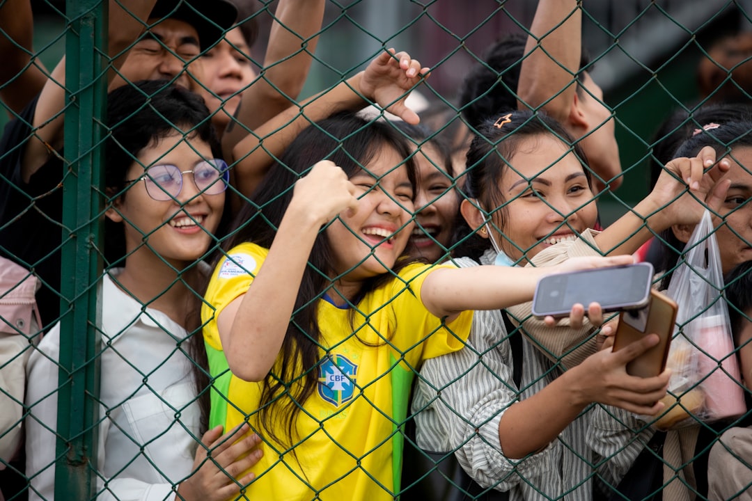 Young fans cheer and take selfies behind a fence. soccer goal celebration yellow jersey players hugging