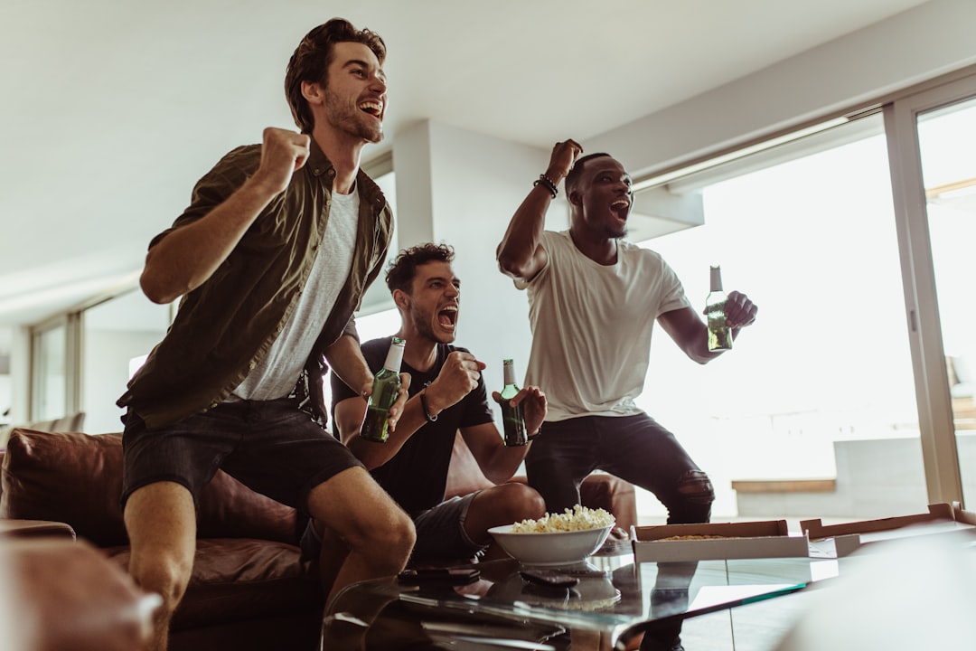 a group of men sitting on a couch and laughing friends watching football, party game night, sports trivia gathering
