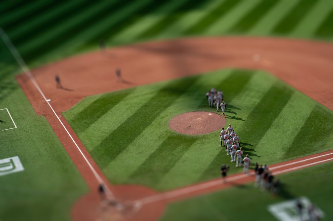 a group of people standing on top of a baseball field baseball stadium aerial view, sunny day game, crowd in stands