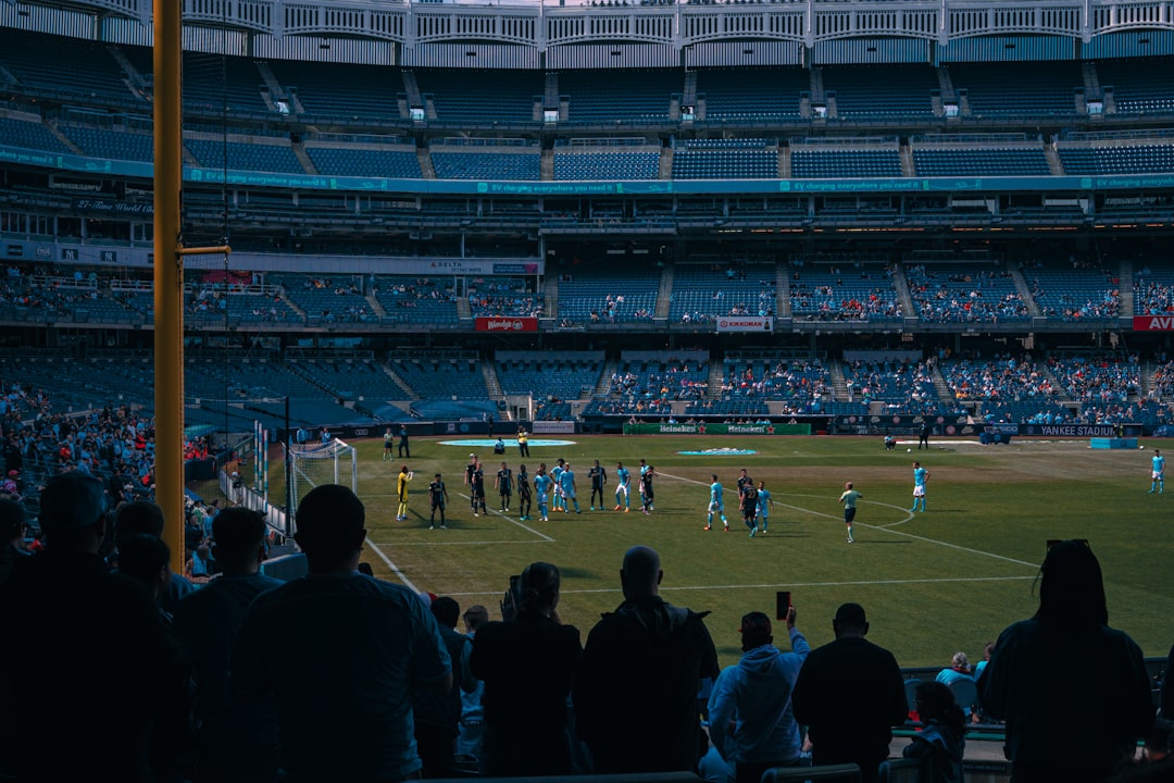 a group of people standing on top of a soccer field football third down play, nfl coaches sideline discussion, packed stadium crowd cheering