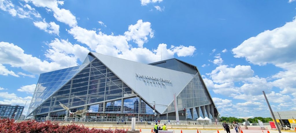 a large glass building with a sky background atlanta falcons defense, nfl linebacker rushing quarterback, mercedes benz stadium interior