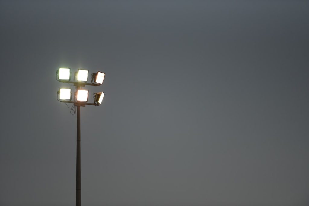 black street light turned on during night time football stadium night game crowd, nfl field action, scoreboard lights