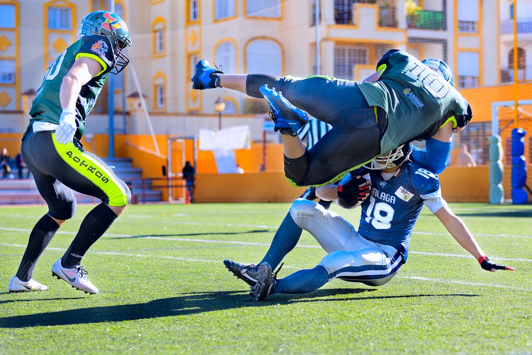 football player in green jersey tackling player in blue jersey football defensive sack, linebacker tackle, quarterback under pressure