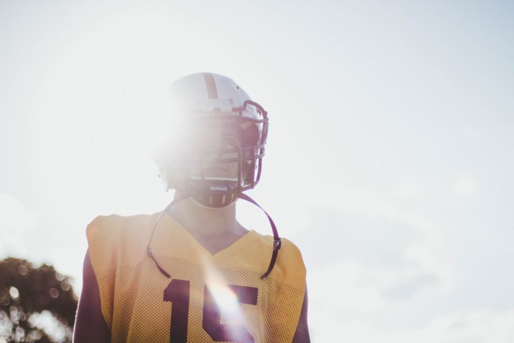 man wearing yellow jersey shirt and white helmet football player silhouette, blurred nfl player, guessing game concept