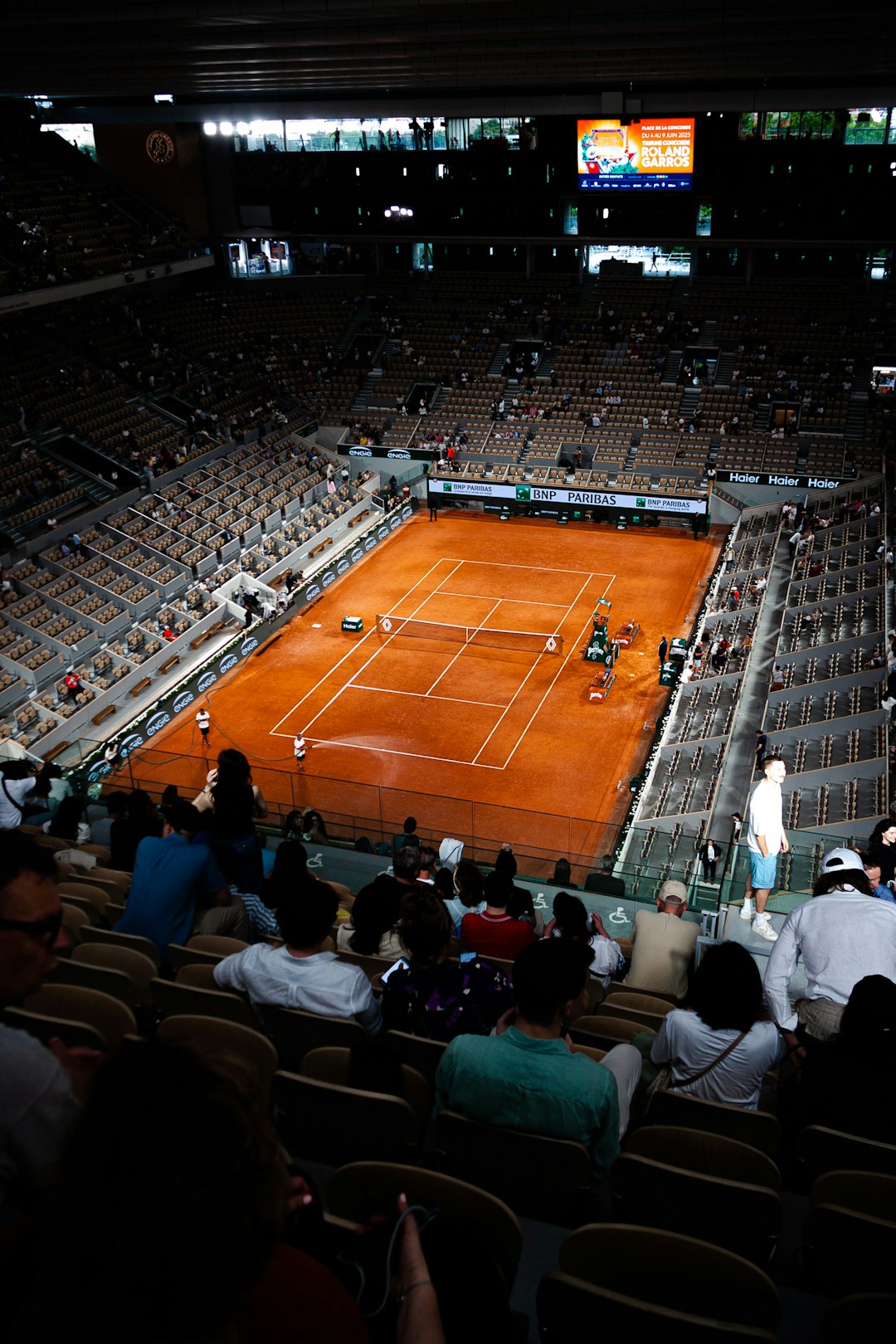 Tennis match in an expansive arena. tennis semifinal match, clay court rally, passionate crowd paris