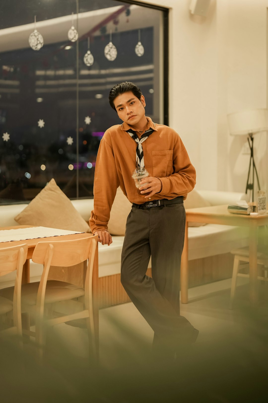 Young man in vintage clothes holding a drink indoors. tall man next to standard door frame, height comparison visual, indoor setting
