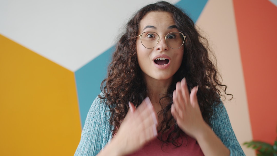 Young woman with curly hair looks surprised. confident woman speaking stage, live podcast event, audience cheering