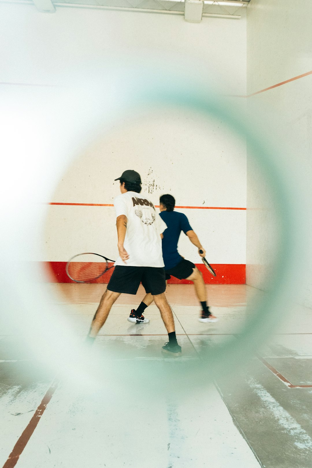 a couple of men standing on top of a tennis court racquetball practice drill, player hitting wall, close up wrist training
