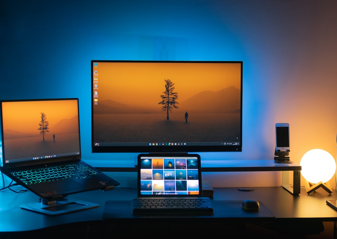 A desk with two monitors and a laptop comparison of remote desktop software on multiple devices, laptop tablet smartphone screens