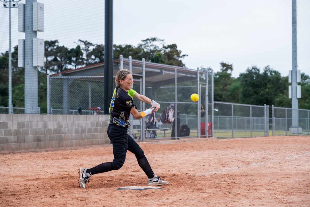 A girl swinging a baseball bat at a ball softball batting stance swing action field