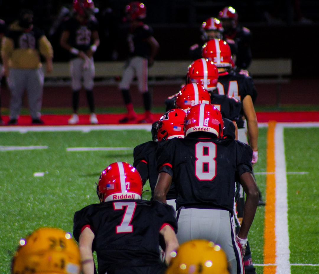 a group of football players lined up on the field college football stadium night game, packed stands, team uniforms close up