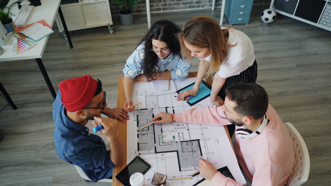 a group of people sitting around a table working on a project team meeting reviewing documents, collaborative planning session, digital knowledge sharing