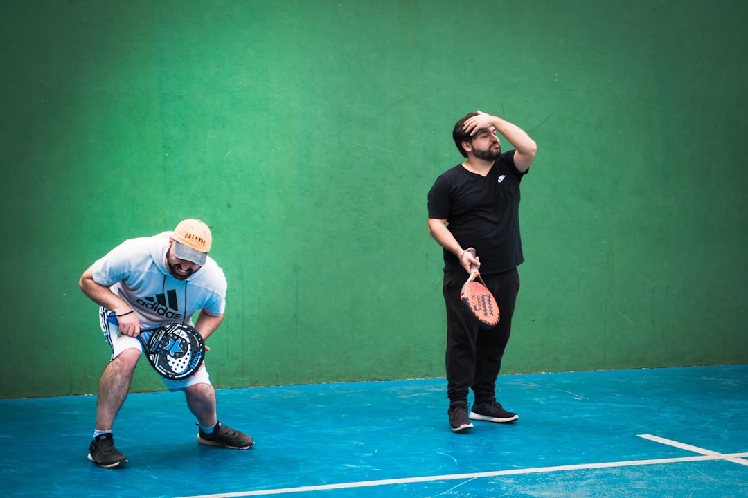 a man holding a tennis racquet on top of a tennis court squash rally close quarters, players near T position, intense movement