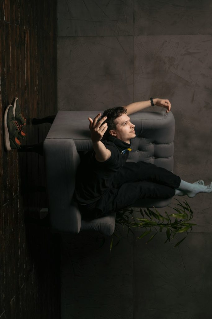 a person sitting in a dark room athlete resting on couch, relaxed muscles, post workout fatigue