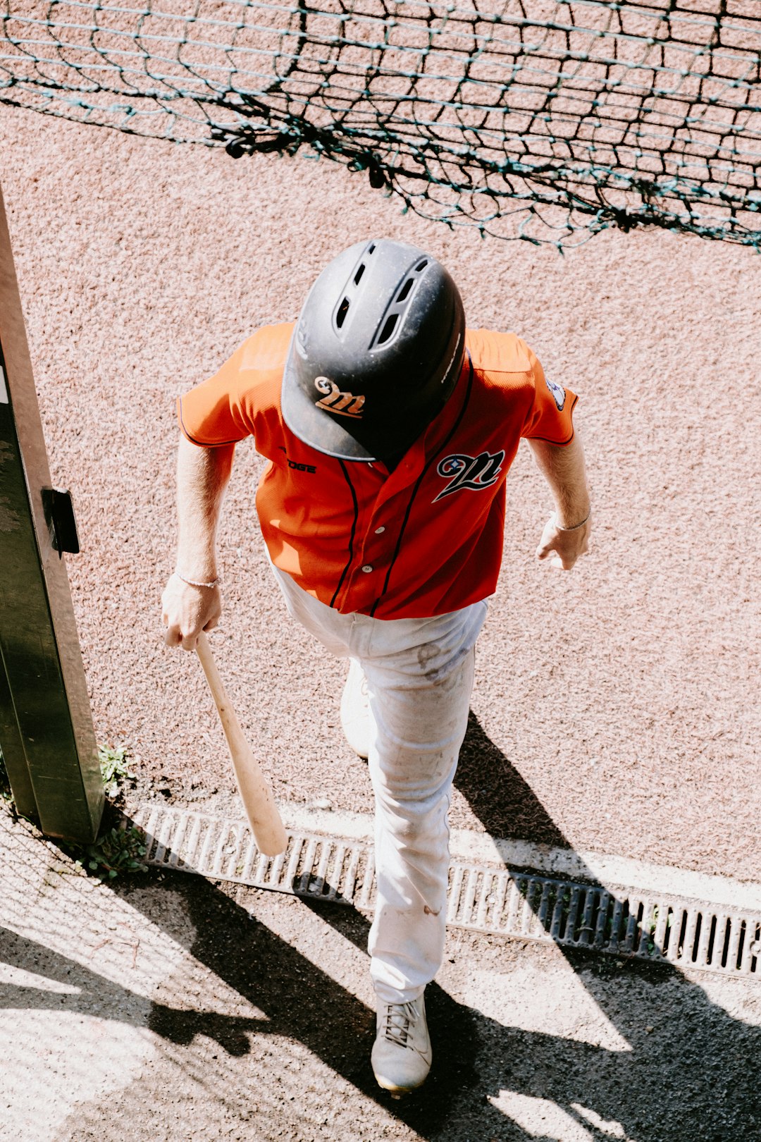 a young boy in a baseball uniform holding a bat softball equipment bat glove helmet ball