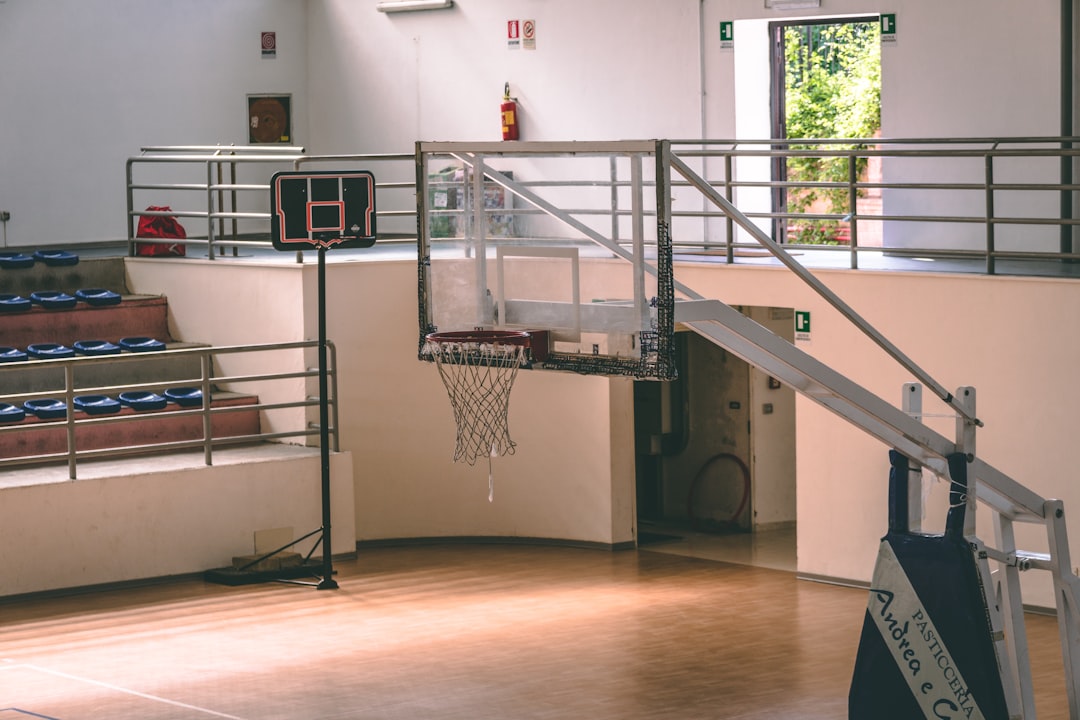 basketball court during daytime basketball rehab practice, athlete stretching, empty gym court, physical therapy session