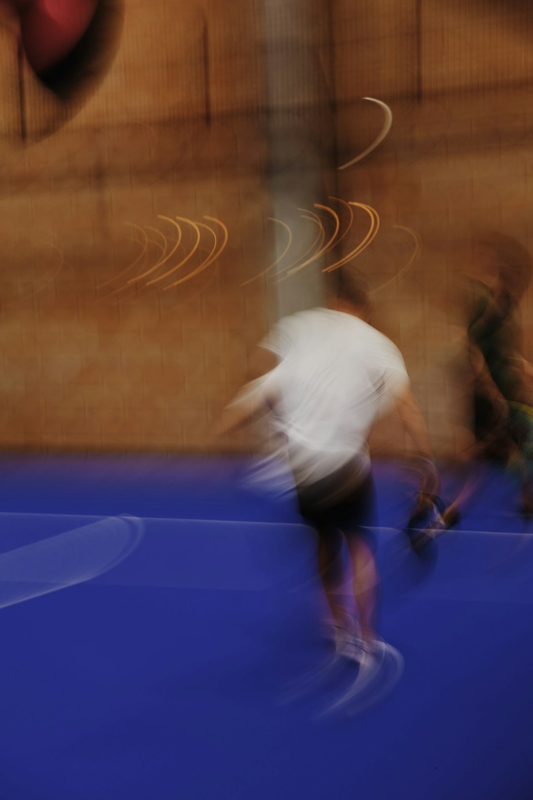 Blurred figures are in motion on a blue surface. racquetball court, player swinging racquet, blue lines on court