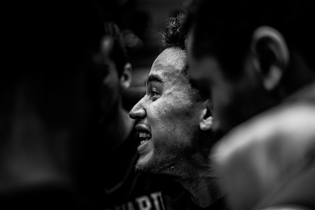 grayscale photo of man in crew neck shirt lebron james talking to young teammates, basketball huddle, lakers bench