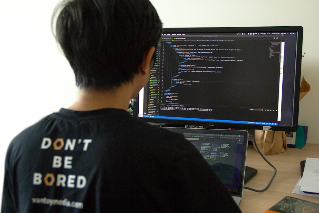 man in black shirt using laptop computer and flat screen monitor developer reviewing css code, code inspection, linting warning screen