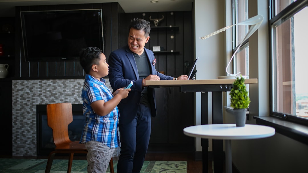 man in blue long sleeve shirt standing beside man in blue and white plaid button up family using laptop, online banking alert, financial protection concept, secure home office