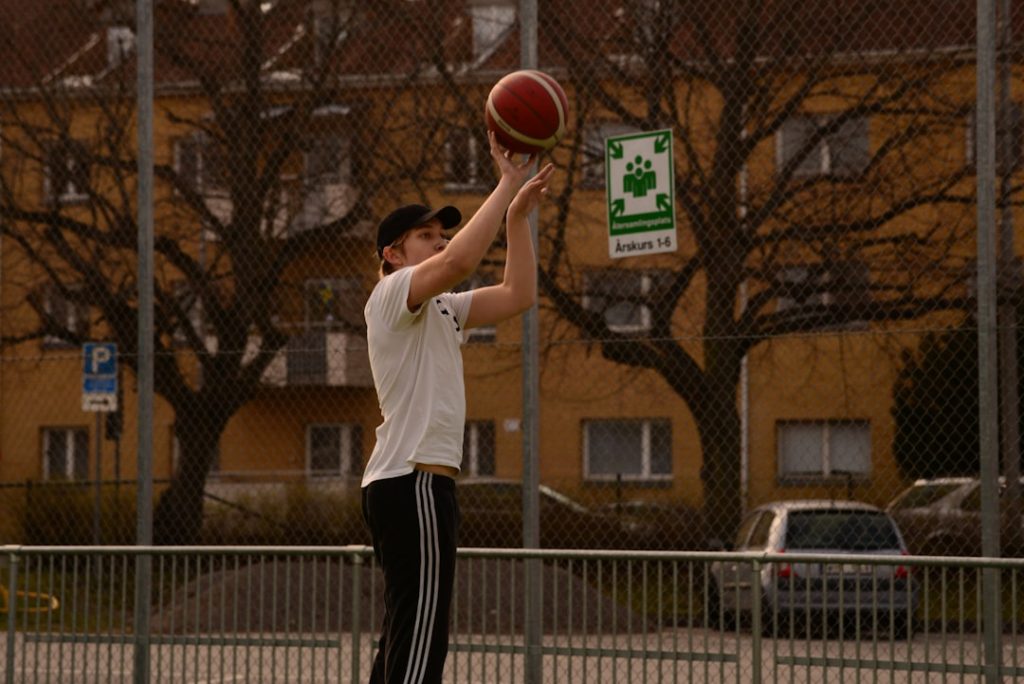 man in white shirt and black pants playing basketball basketball player close range shot, youth gym practice, proper shooting form