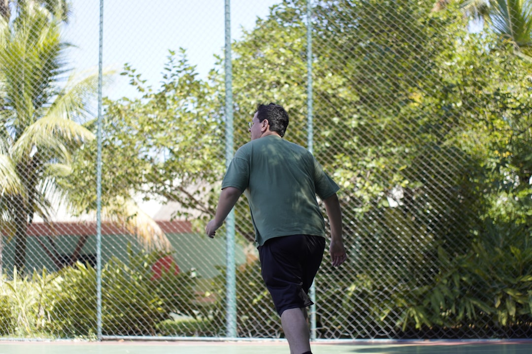 Man playing tennis on a sunny day beginner tennis player swinging racket, tennis forehand motion, outdoor tennis court action