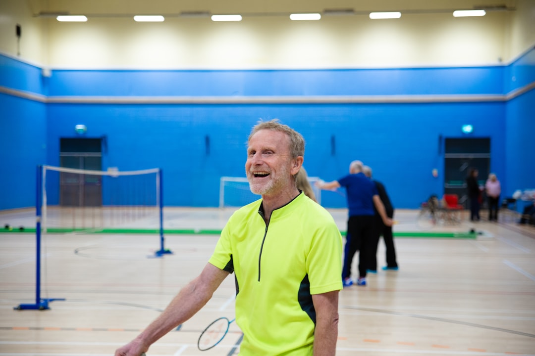 Man smiling in a badminton court padel player near net preparing smash indoor court