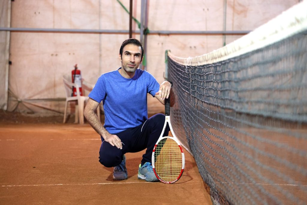 Man with tennis racket on court near net padel player near net preparing smash indoor court