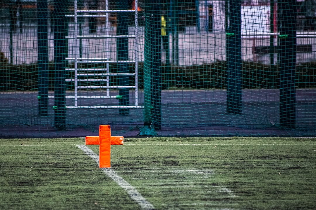 Orange marker on a green sports field football kickoff, ball in end zone, referee signal touchback