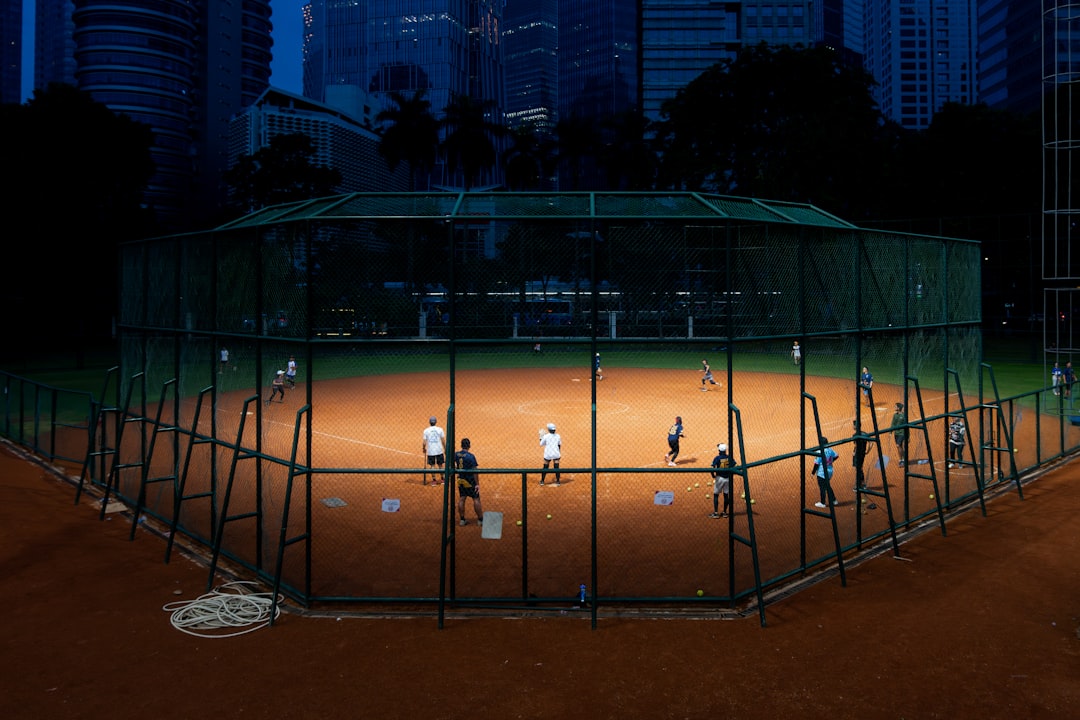 People playing baseball on a lit field at night. softball field diagram bases infield outfield