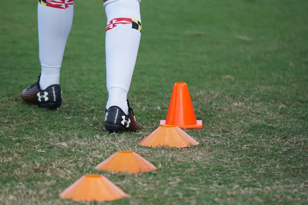 person standing on grass football player jogging training field cones