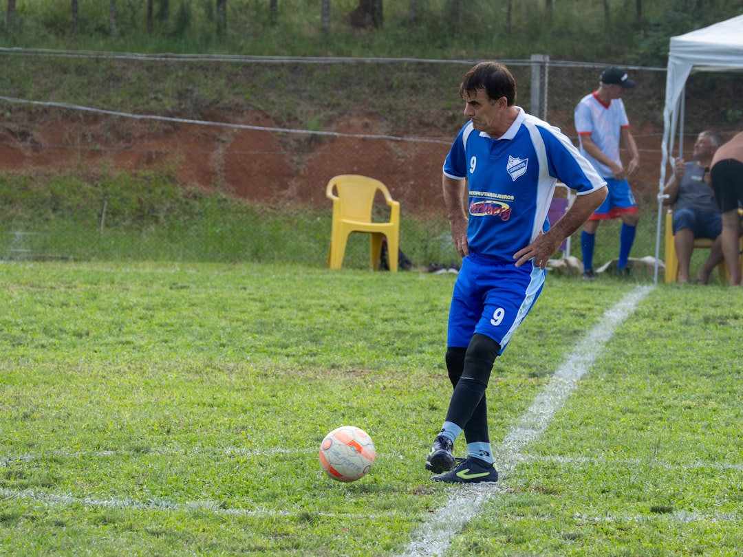Soccer player in blue uniform with ball on field football punt, ball near goal line, special teams players