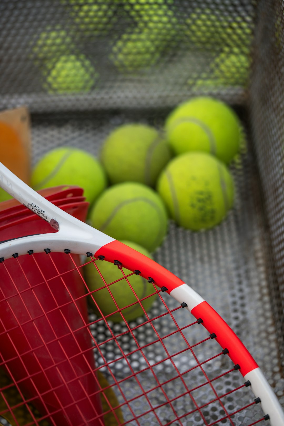 Tennis racket and balls in a metal basket tennis rackets lineup on court, beginner tennis equipment, tennis balls and rackets