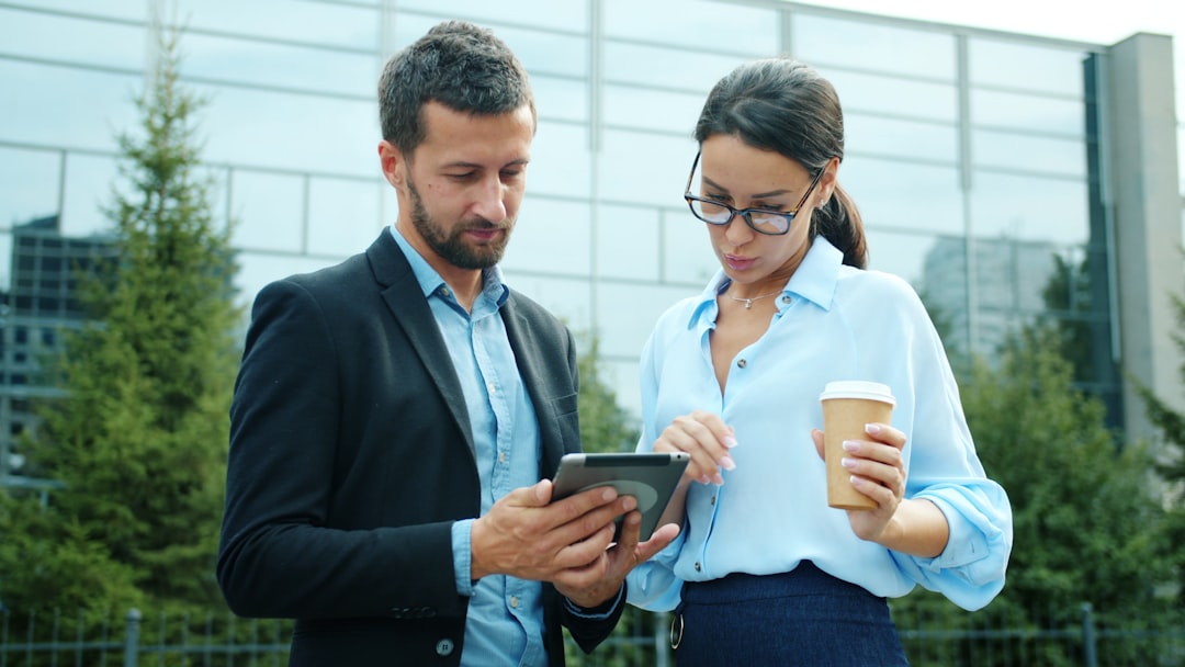 Two business people looking at a tablet outside. client meeting, crm dashboard, commercial buildings
