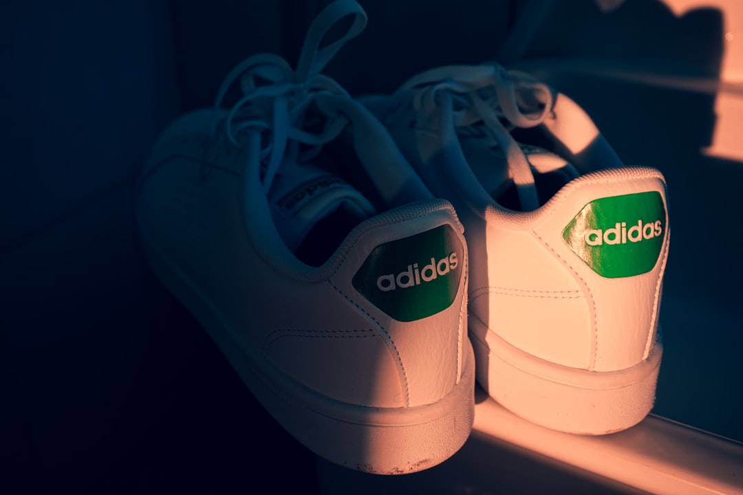 white adidas low top sneakers parent tying soccer cleats, youth player sitting on bench, adidas logo close up, pre game preparation