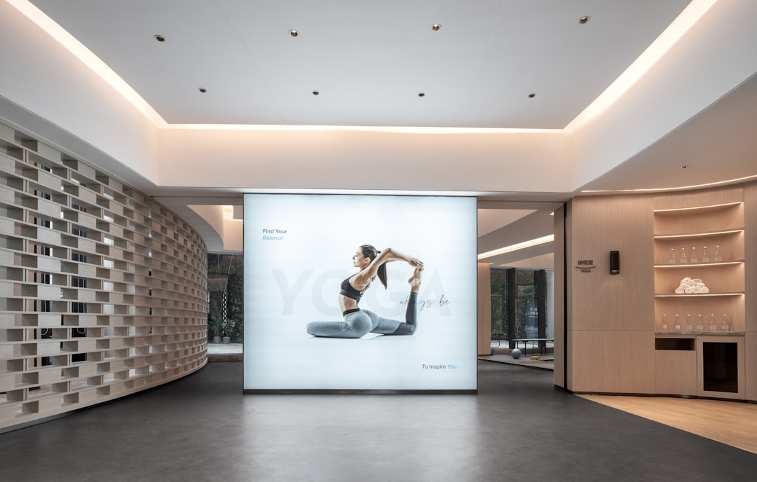Woman in yoga pose on illuminated display group pilates class studio, people stretching on mats, bright fitness space