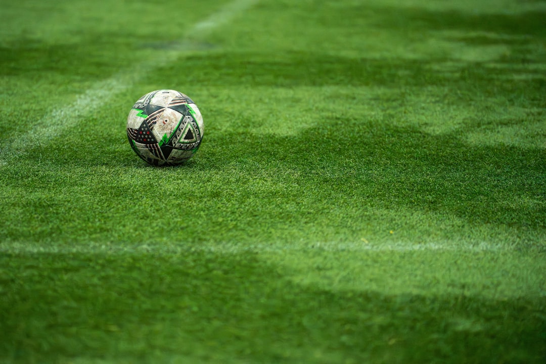 A soccer ball rests on a green field. fantasy football manager, waiver wire, trade analysis, weekly lineup