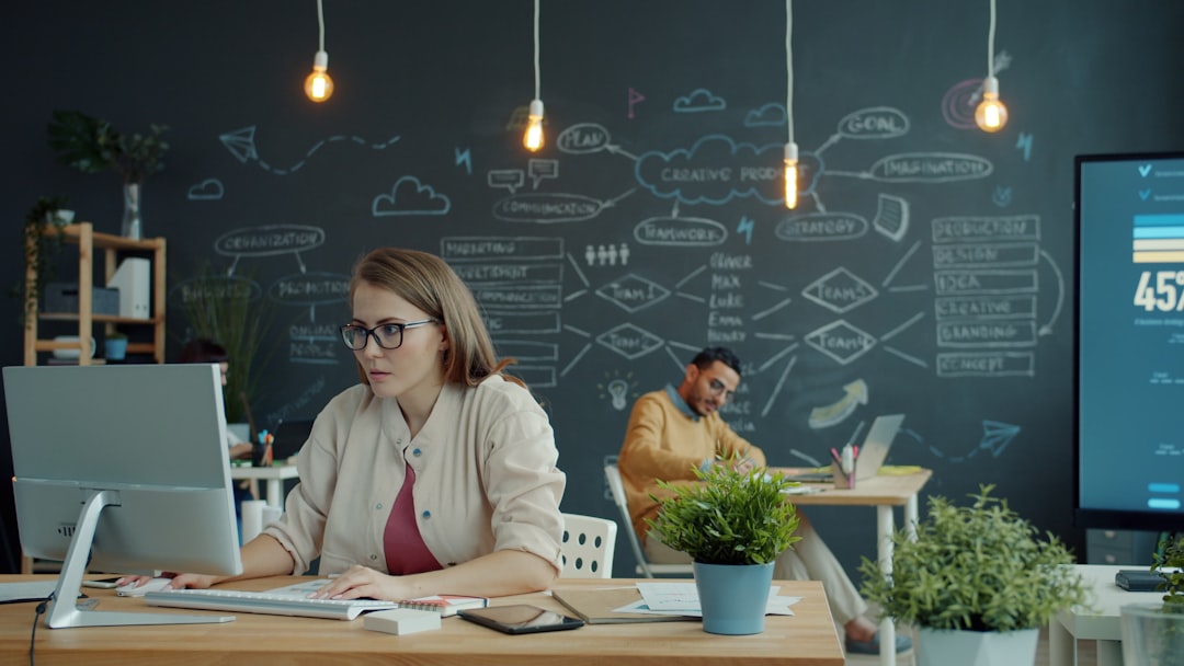 Woman working on computer in modern office with chalkboard. growing business startup team, scaling technology, cloud computing concept, digital growth chart